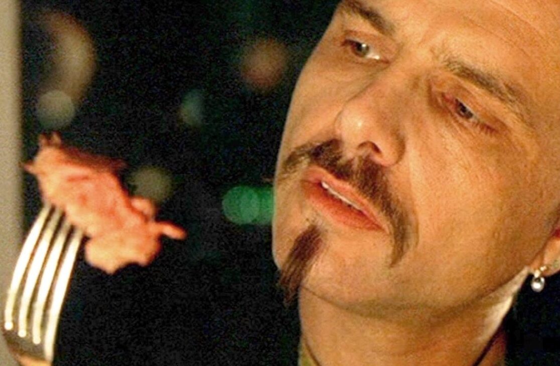 Un uomo guarda con aria compiaciuta un pezzo di bistecca su una forchetta